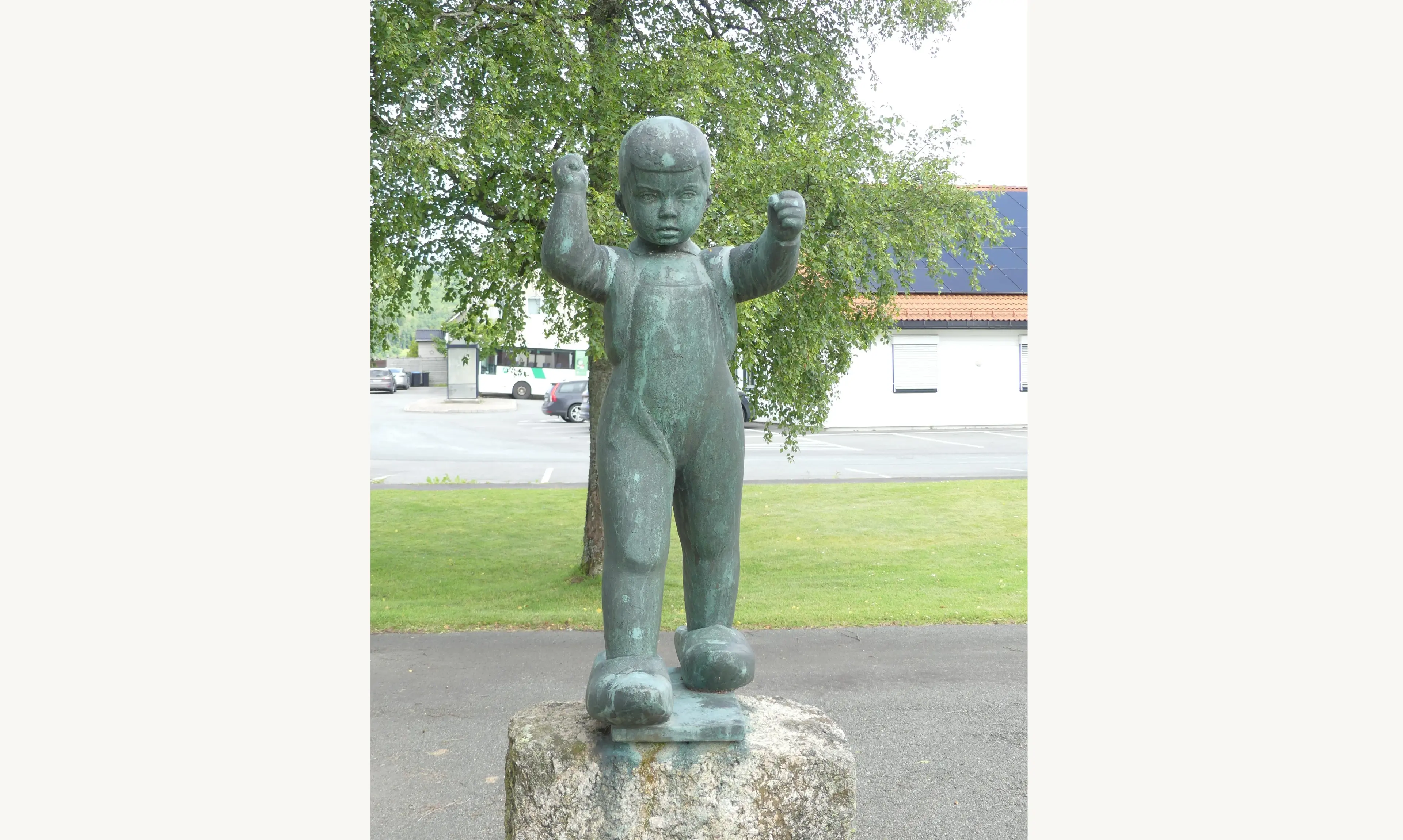 Bronseskulptur av en liten gutt i overall som står i farens altfor store tresko, på en granittsokkel